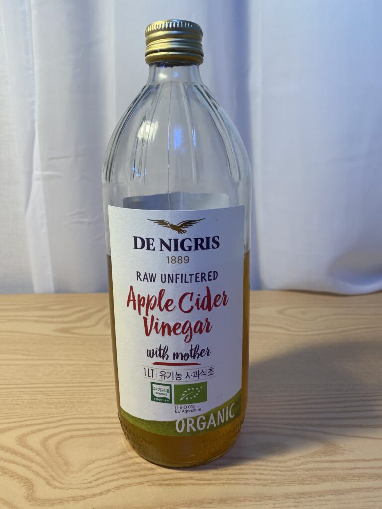 A minimalist setting featuring a glass of diluted apple cider vinegar with cinnamon, illustrating the Korean Biohacking Routine for metabolic health and mental clarity by Bridget June.