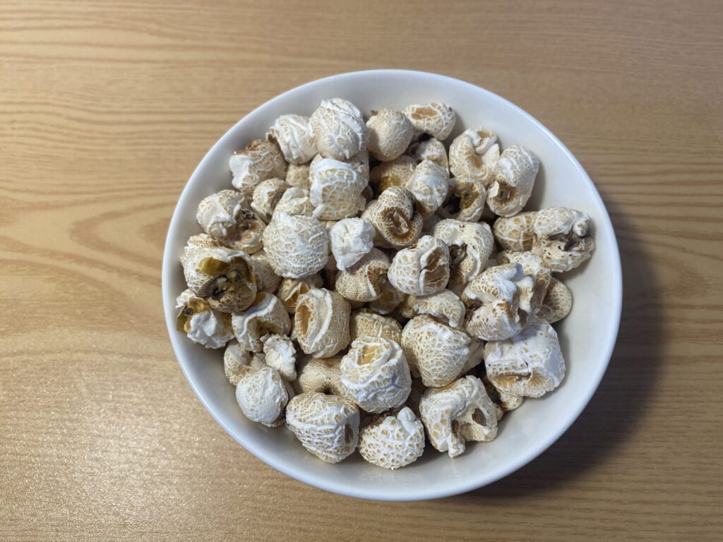 A close-up of a small bowl of gangnaengi placed next to a large glass of water. This illustrates the "Water Balloon Protocol" where hydration creates fullness, preventing overeating of the snack.