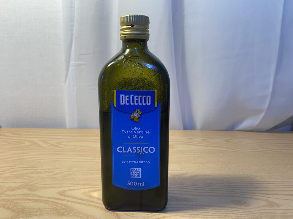 올레오칸탈의 주요 공급원임을 나타내는, 신선한 올리브 가지와 함께 거친 나무 탁자 위에 놓인 고품질 엑스트라 버진 올리브 오일 병.