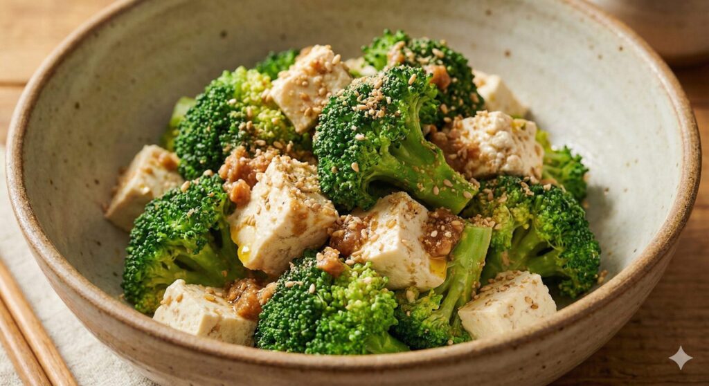 설포라판과 식물성 단백질을 위해 된장 드레싱으로 버무리고 으깬 통깨를 뿌린 완성된 브로콜리 두부 무침 플레이팅.