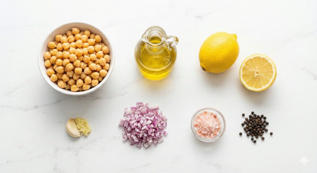 병아리콩, 올리브 오일, 레몬, 마늘, 양파, 핑크 솔트 등 병아리콩 매쉬 샐러드 레시피를 위해 정확히 계량된 원재료 모음.