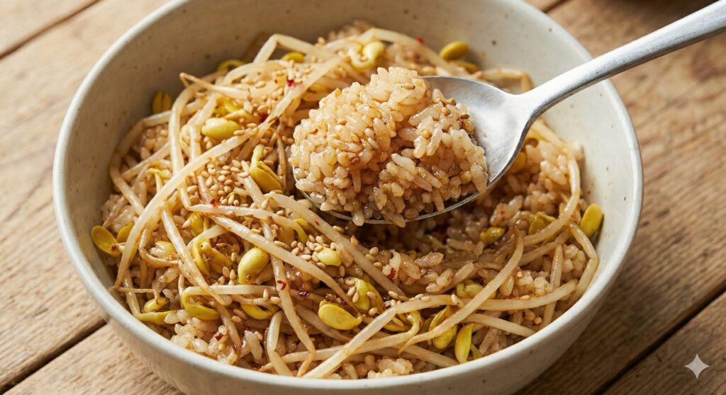 A close-up of a finished bowl of Kongnamul Bibimbap, with generous soybean sprouts mixed with rice and drizzled with the savory soy seasoning sauce, ready for a detox meal.