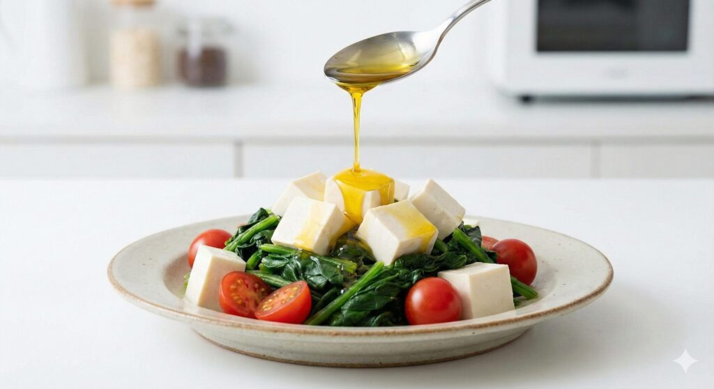 Raw perilla oil being drizzled over a fresh salad of tofu, spinach, and tomatoes, demonstrating the heat-free biohacking consumption method.