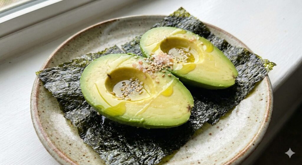 Fresh avocado halves placed on crisp seaweed sheets, illustrating a biohacking snack where healthy fats aid the absorption of fat-soluble vitamins.