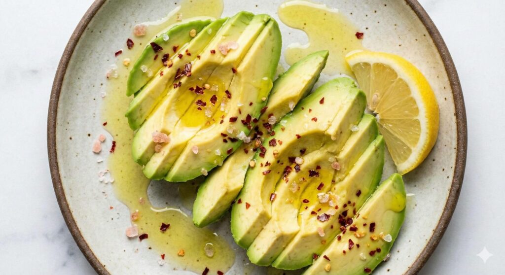 칼륨과 건강한 지방을 보충하기 위한 간단한 바이오해킹 간식인, 레몬즙을 뿌리고 핑크 솔트를 곁들인 신선한 아보카도 슬라이스.