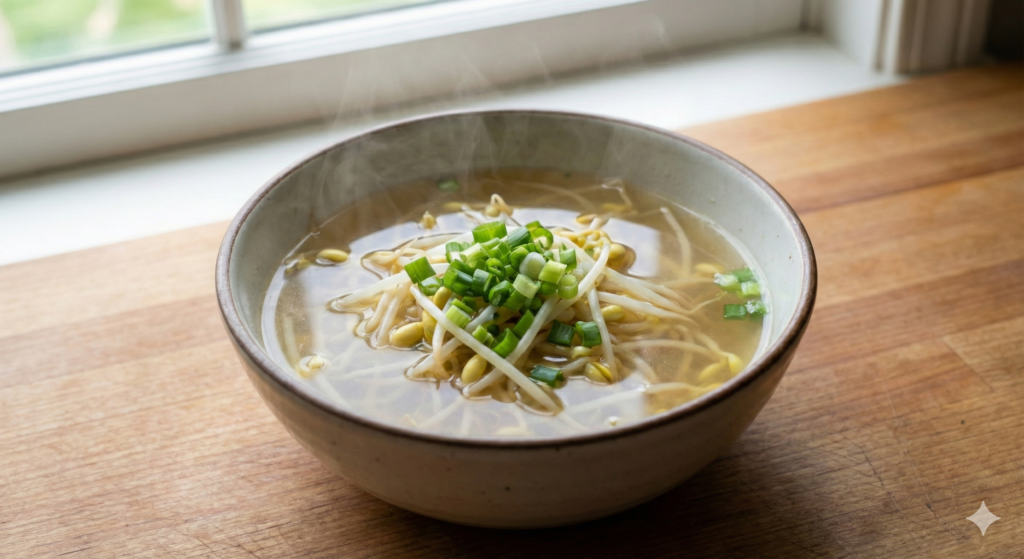 A steaming bowl of clear, pure soybean sprout soup garnished with fresh green scallions, representing the ultimate liver-cleansing and hydrating biohack protocol.